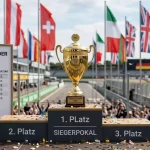 Formel-1-WM-Pokal mit Flaggen und Saisonkalender im Hintergrund