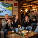 Diverse Gruppe von Motorsport-Fans vor einem Bildschirm beim Rennschauen