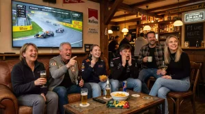 Diverse Gruppe von Motorsport-Fans vor einem Bildschirm beim Rennschauen